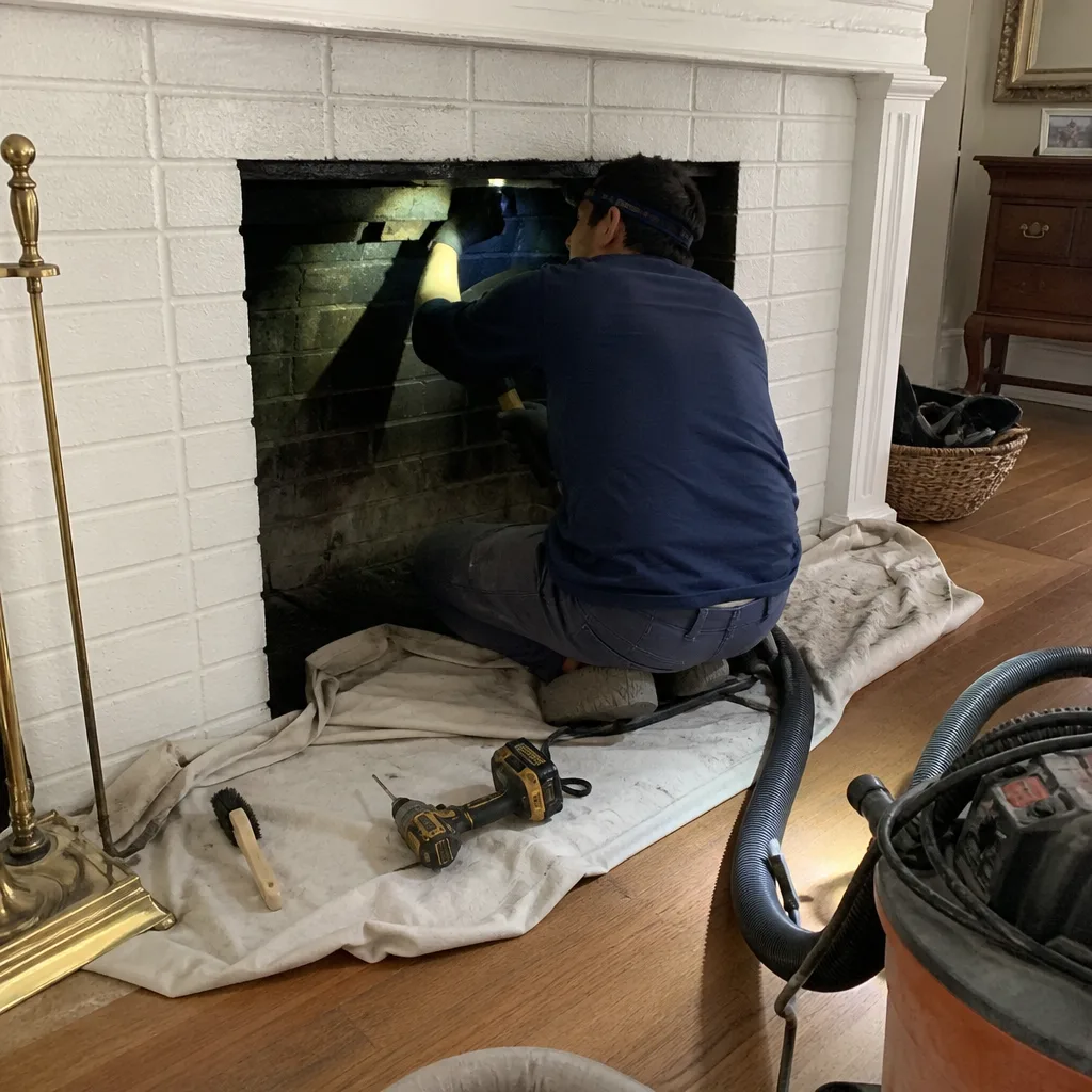 Professional technician performing a chimney fireplace inspection and cleaning